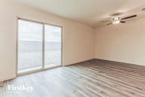 a living room with wood floors and a large window and a ceiling fan