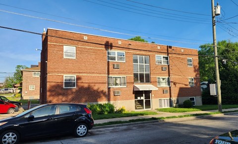 A black car is parked in front of a red brick building.