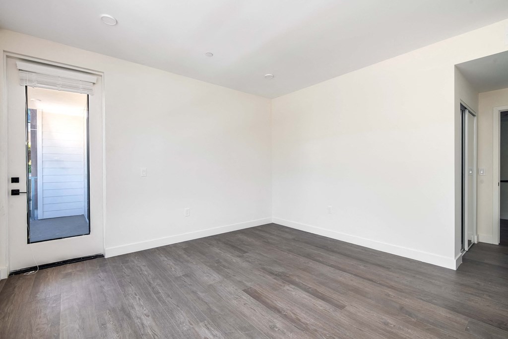 an empty living room with white walls and wood flooring
