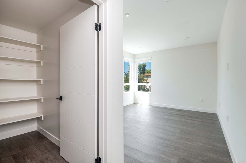 a room with white walls and a white closet and a window