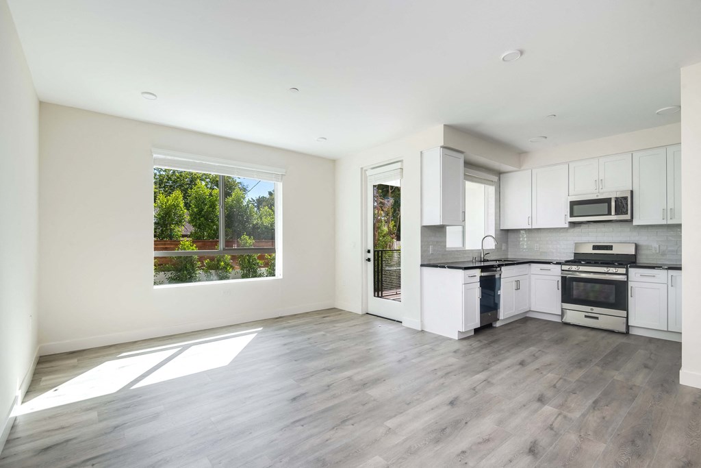 an empty kitchen with white cabinets and a large window