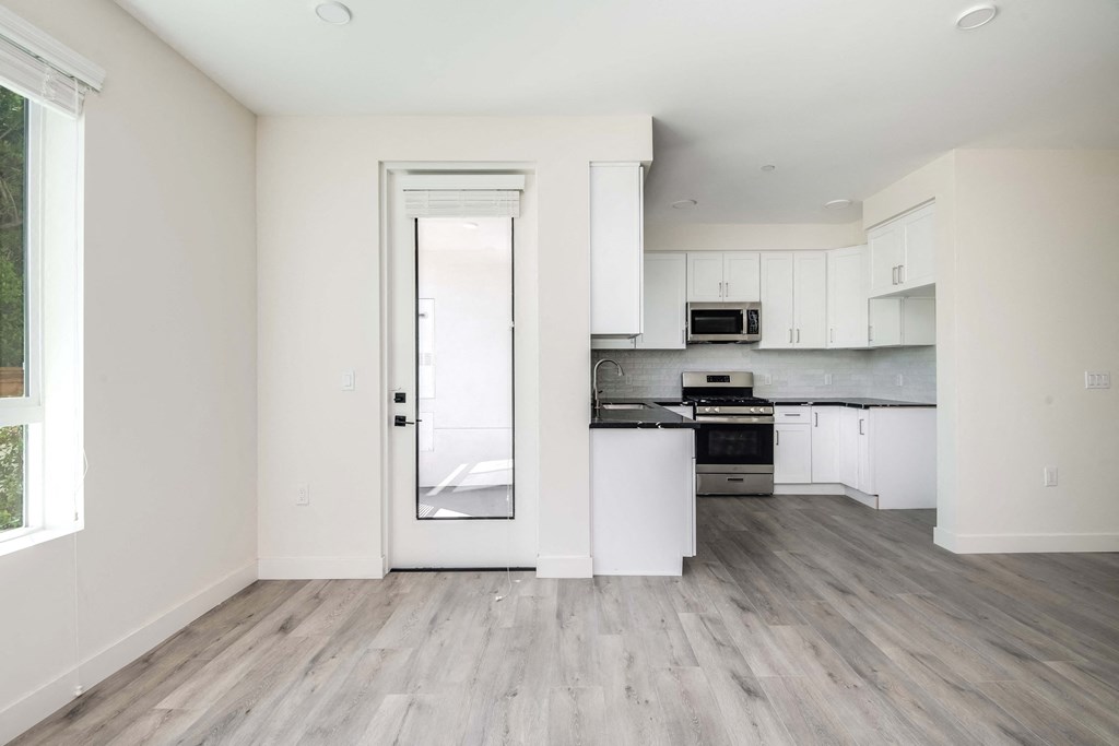 an empty kitchen with white cabinets and a glass door
