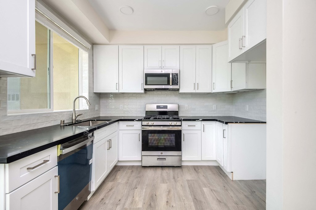 a kitchen with white cabinets and black counter tops
