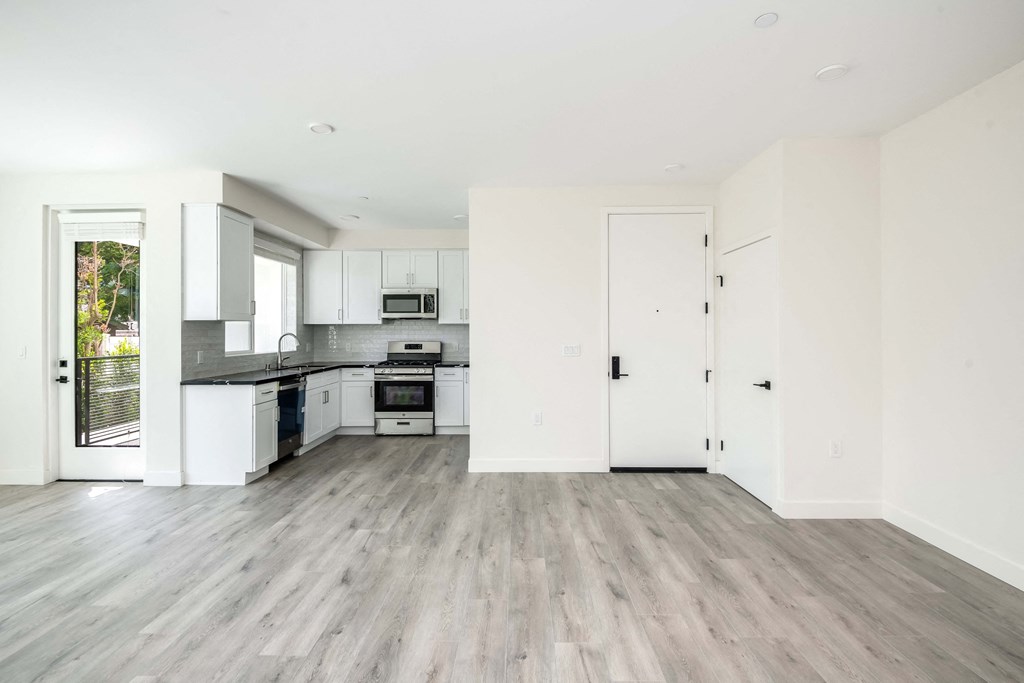 an empty kitchen with white walls and wood floors