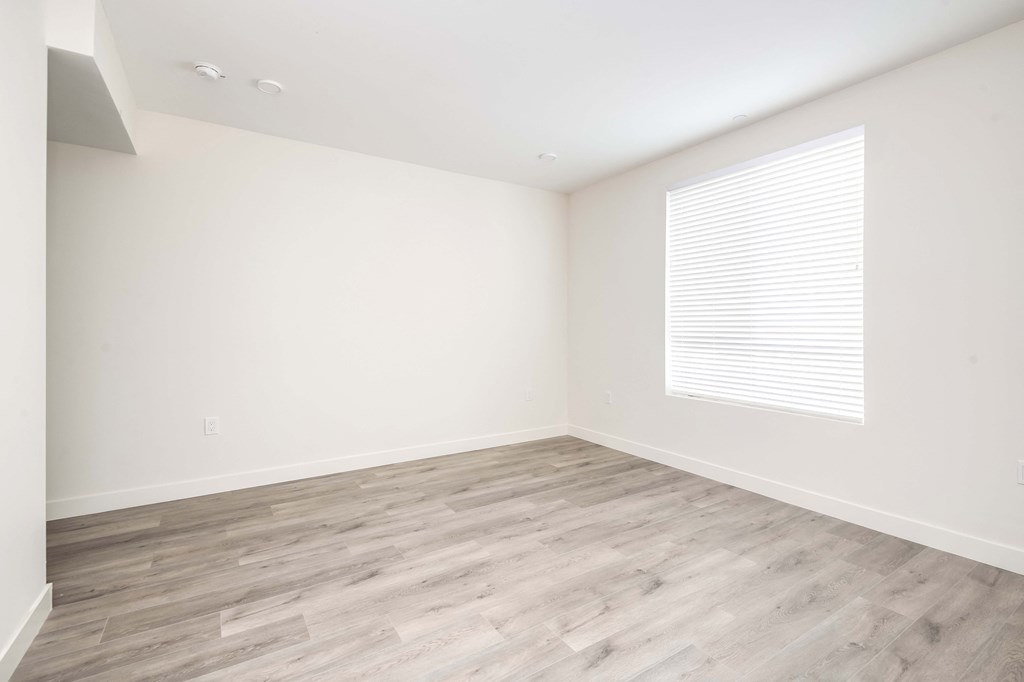 an empty room with wood flooring and a window