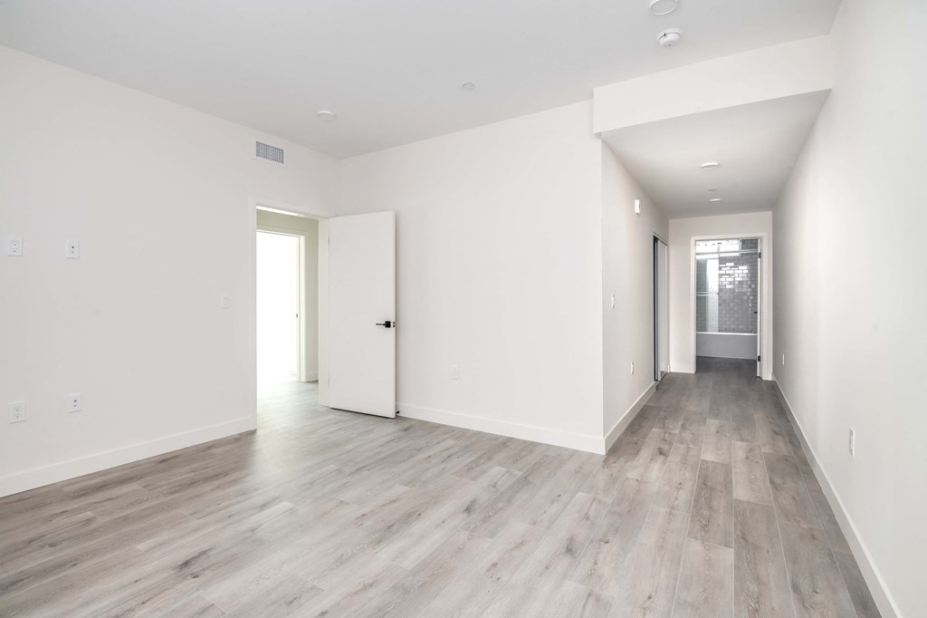 an empty room with white walls and wood floors
