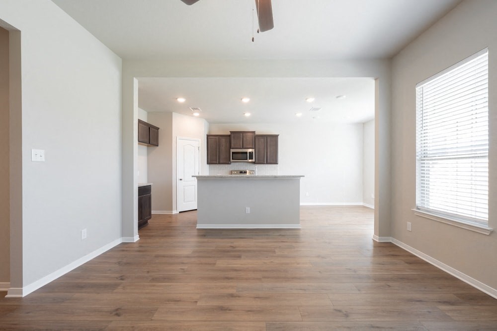 an empty living room and kitchen with white walls and wood floors