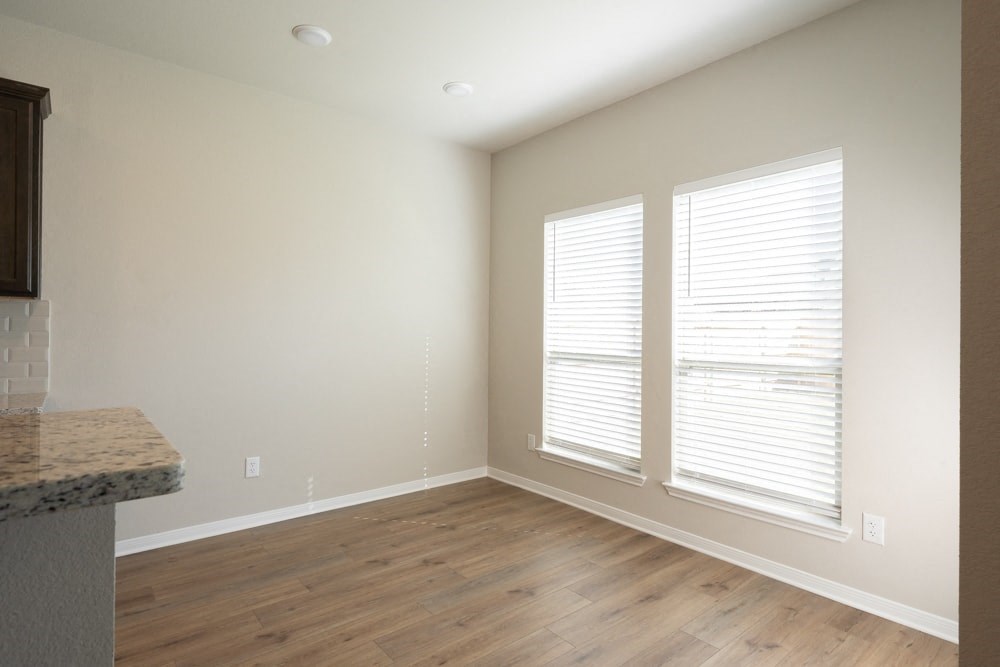 a living room with a hard wood floor and three windows