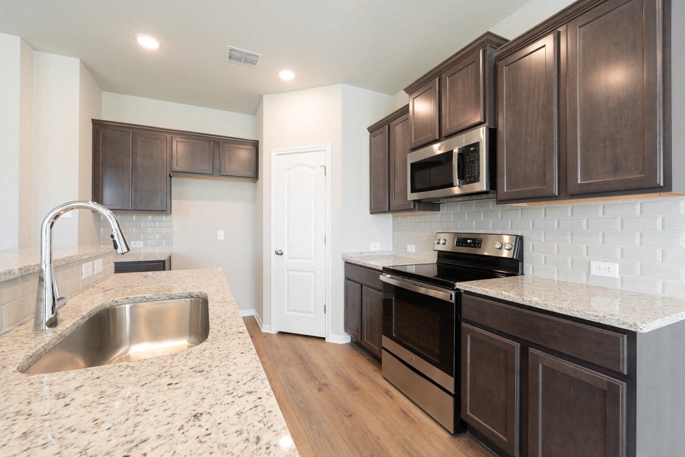 a kitchen with dark wood cabinets and granite counter tops