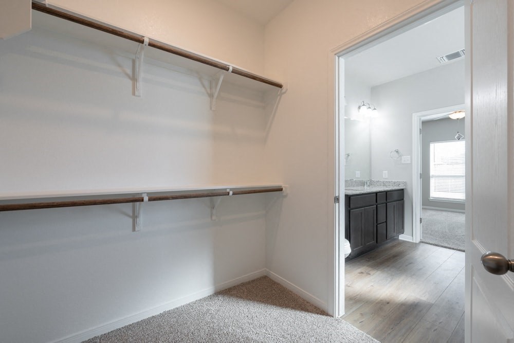 a walk in closet in a bathroom with a mirror and a sink