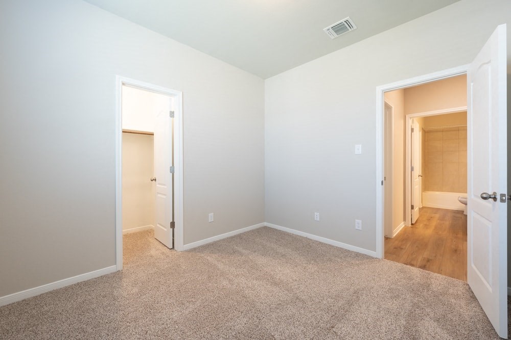 a bedroom with a door to a hallway and a carpeted floor