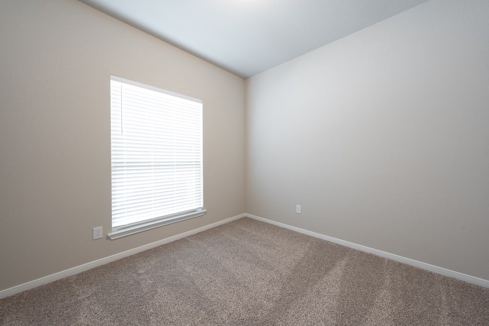 an empty room with a large window and carpet