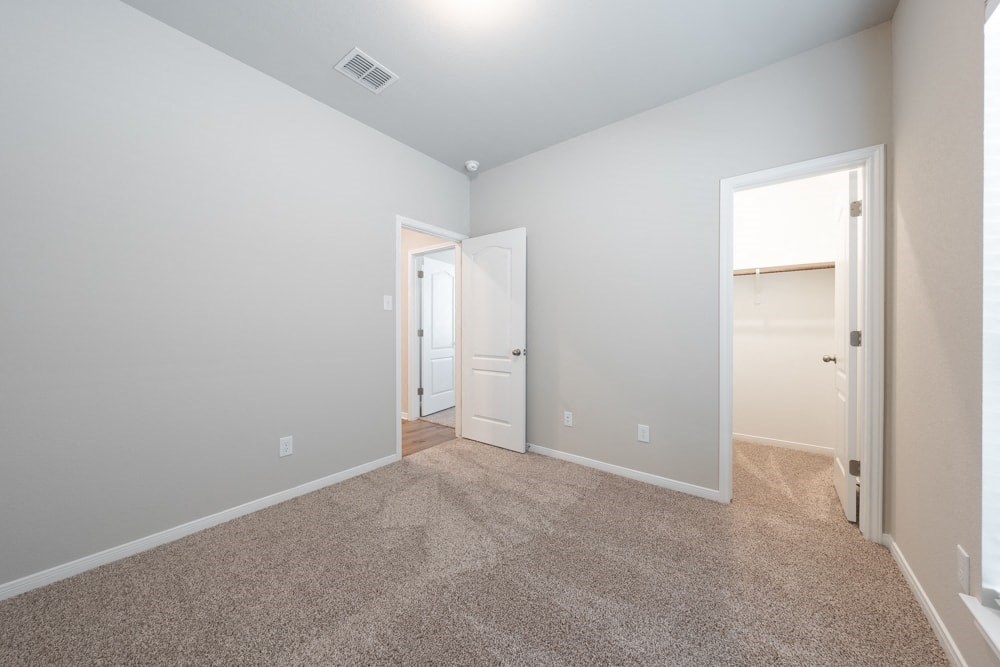 a bedroom with a carpeted floor and a door to a closet