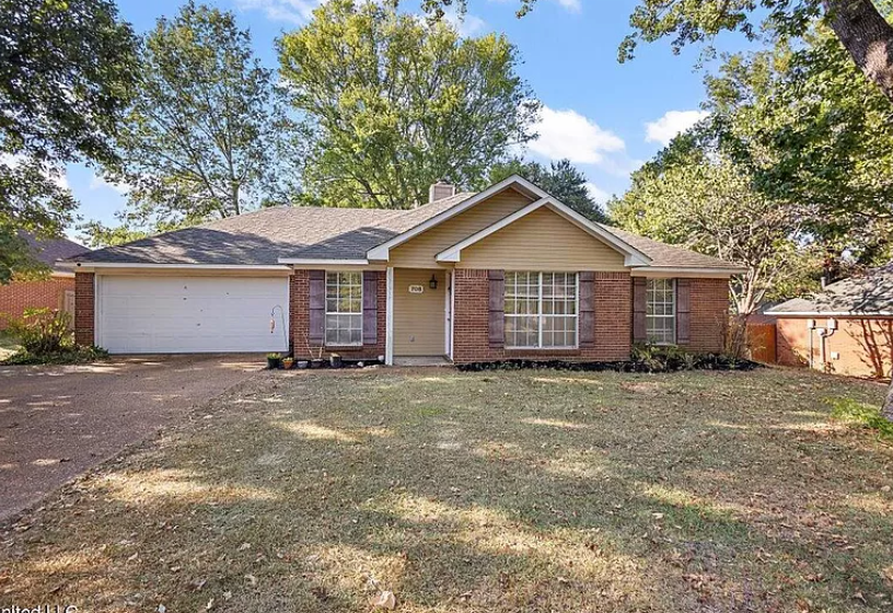 a brick house with a yard and a white garage