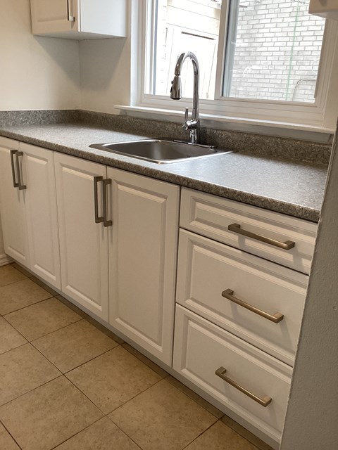 a kitchen with white cabinets and a sink and a window