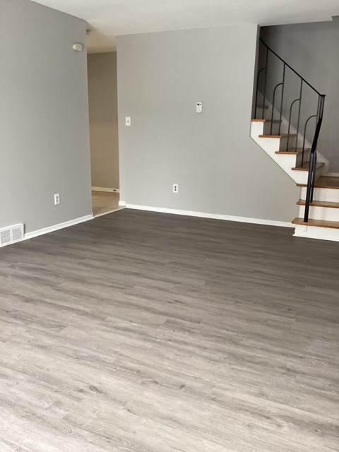 an empty living room with wood floors and a staircase