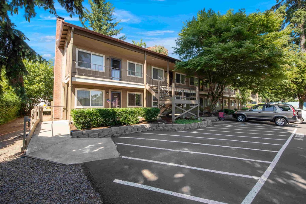 an apartment building with a parking lot and a car in front of it