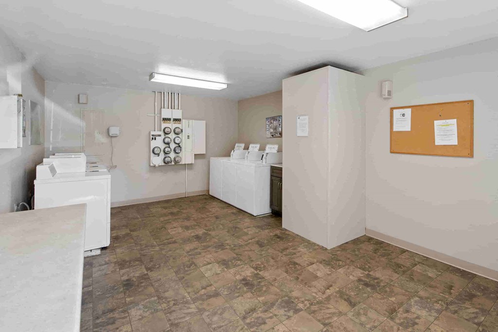a spacious laundry room with white appliances and a counter with a sink