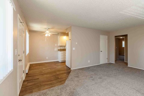 A spacious room with a carpeted floor and a ceiling fan.