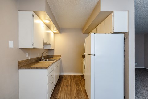 A kitchen with white cabinets and a white refrigerator.