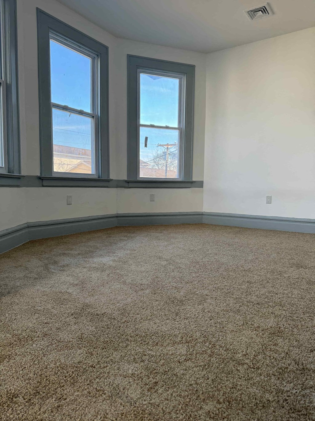an empty room with three windows and a carpet floor