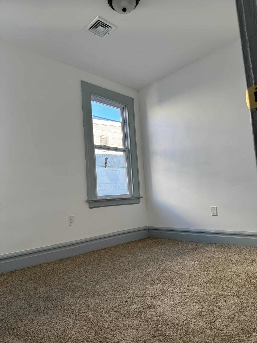 an empty room with a window and a carpet
