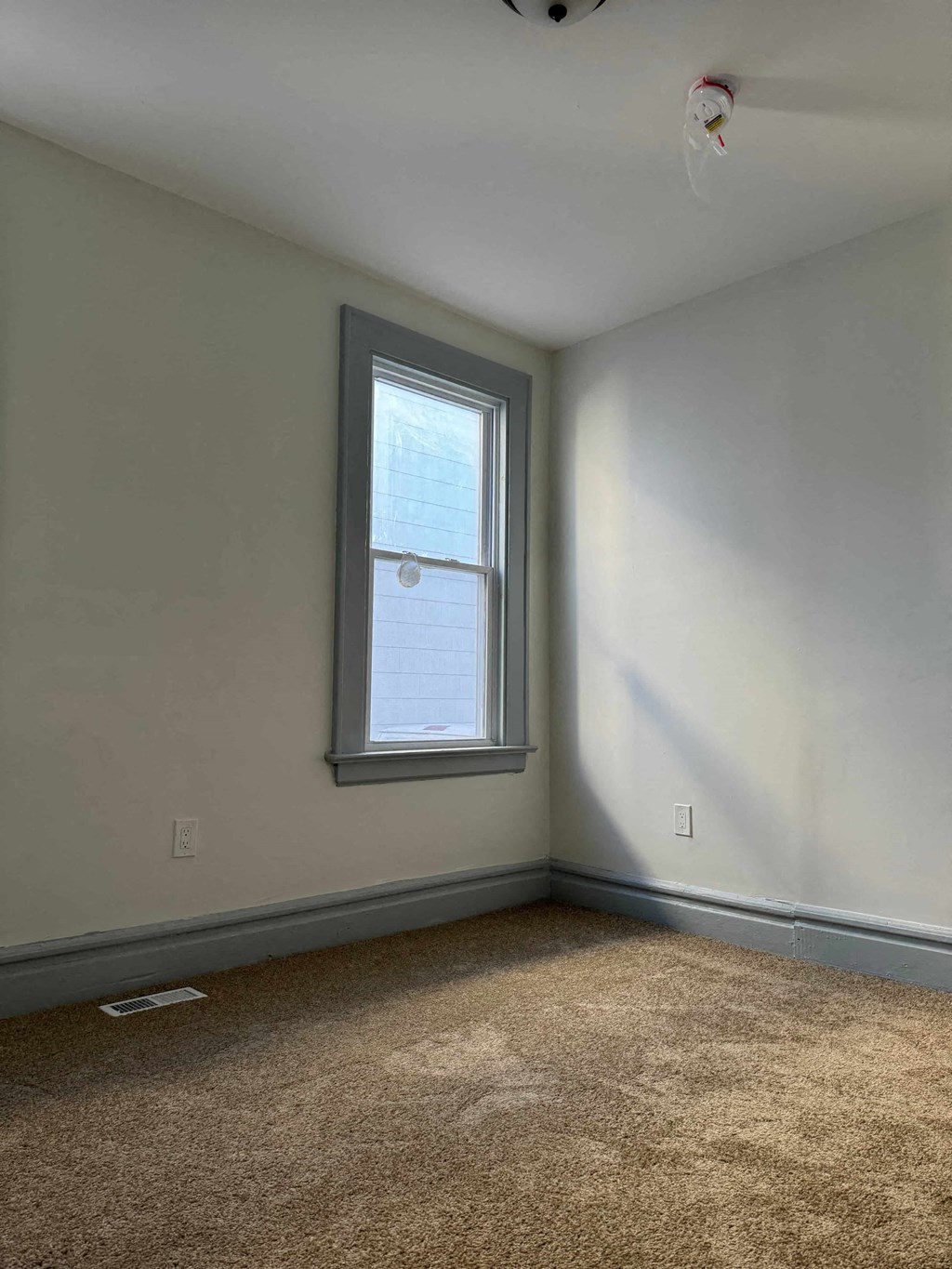 a white room with a window and a carpet