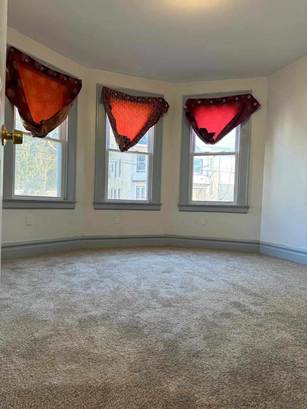 an empty room with three windows with red curtains