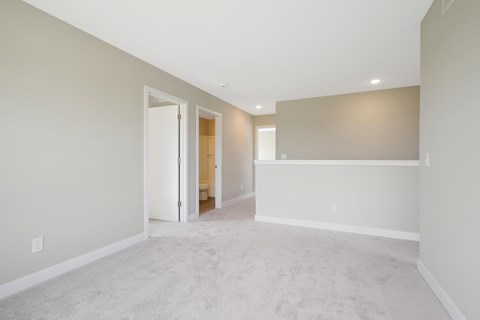 a spacious living room with white carpet and a white wall