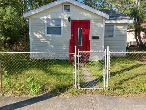 a small white house with a red door and a chain link fence
