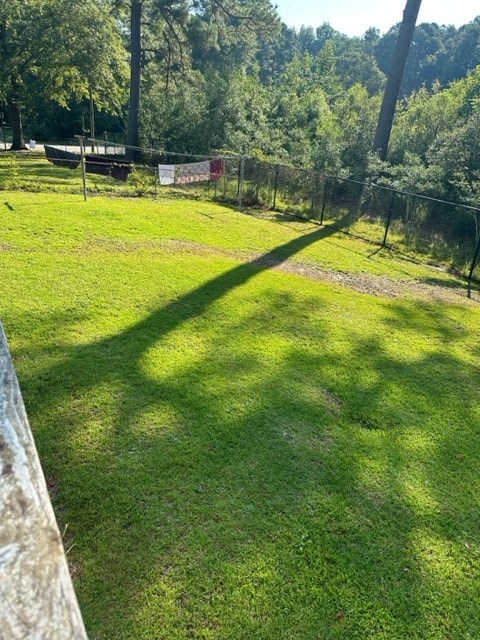 A grassy field with a fence and trees in the background.