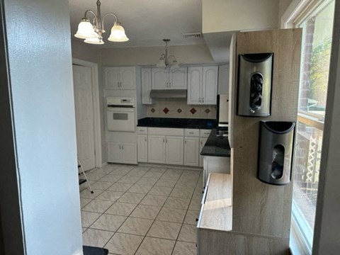 A kitchen with white cabinets and a black stove top.