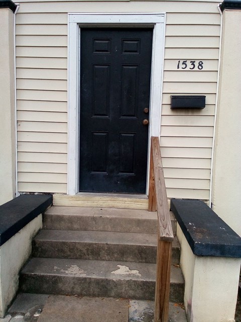 a house with a black door and stairs in front of it