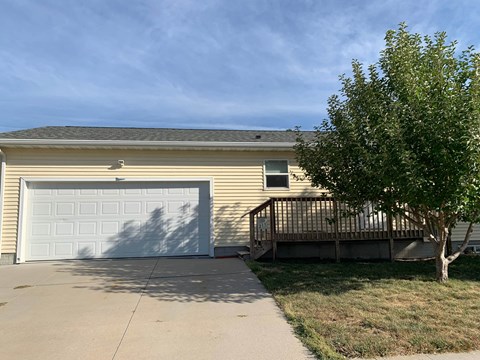 a yellow house with a garage door and a tree