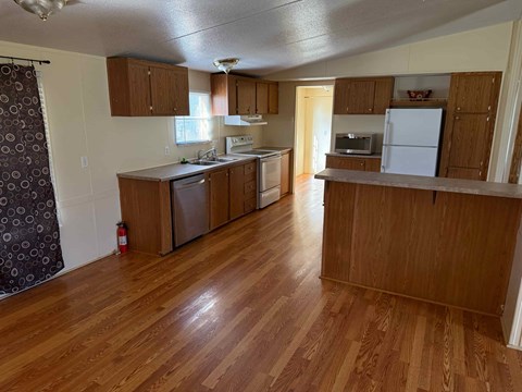 an empty kitchen with wood flooring and wooden cabinets