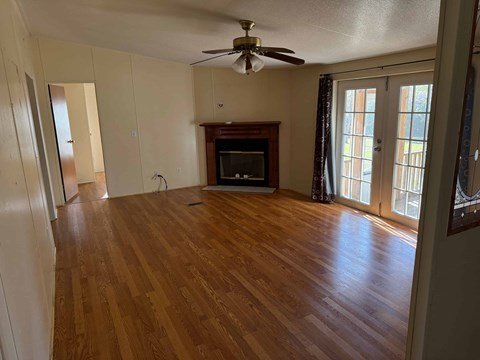 an empty living room with a wood floor and a fireplace