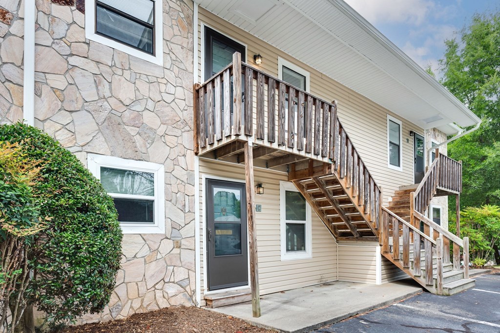 the front of a house with a deck and a stone facade