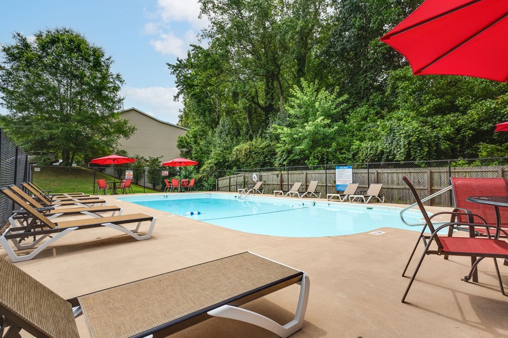 our resort style swimming pool is surrounded by chairs and umbrellas