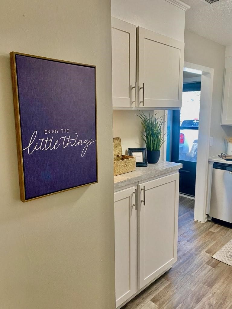 a kitchen with a sign on the wall and white cabinets