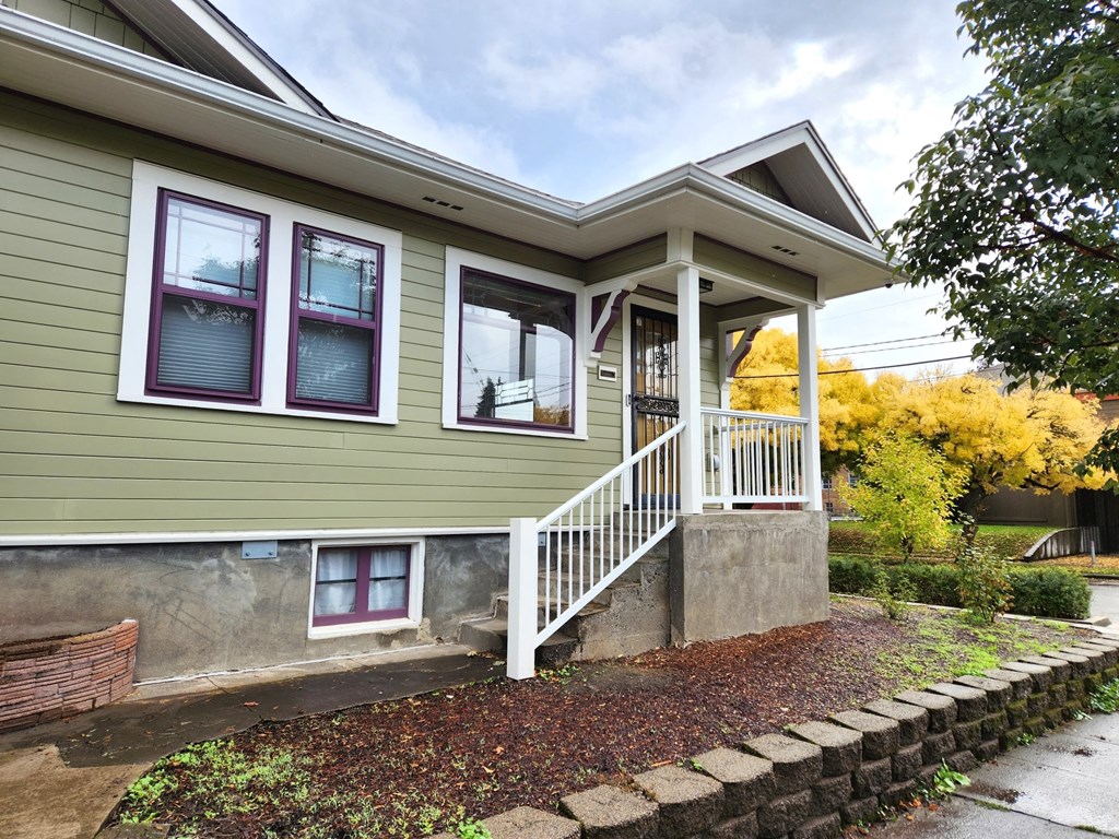 A house with a green siding and a white porch.