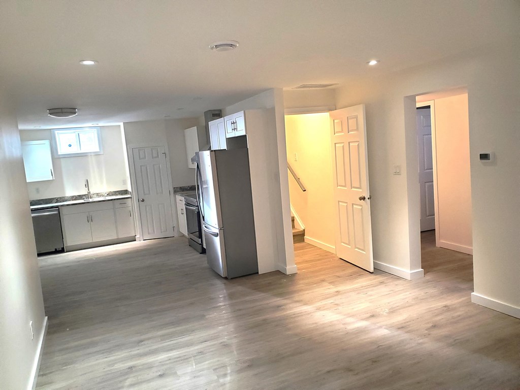 a renovated living room with a kitchen and a refrigerator