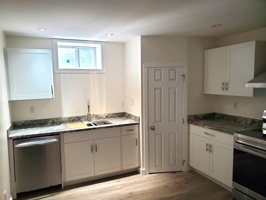 a kitchen with white cabinets and a sink and a door