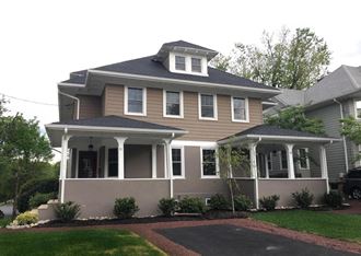 a tan house with a gray roof and a driveway