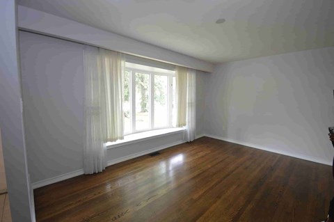 an empty living room with wood floors and a window