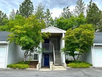 a gray house with a blue door and two trees