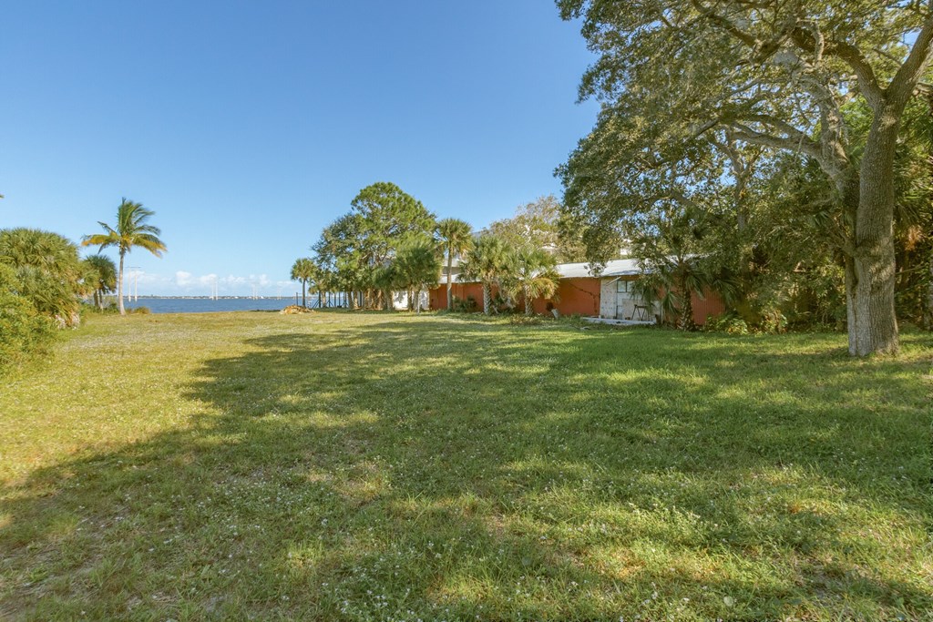 a house on the side of a field with grass and trees
