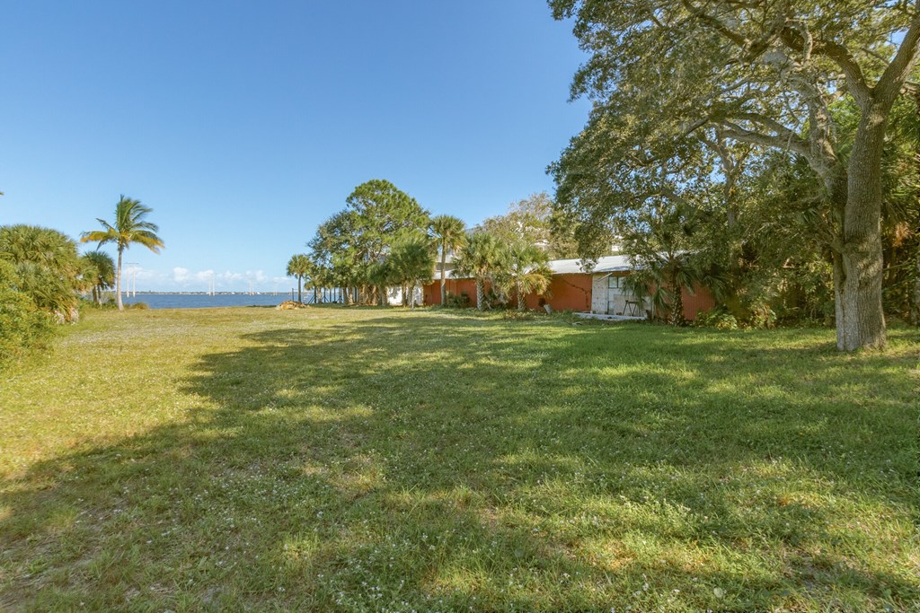 a house on the side of a field with grass and trees