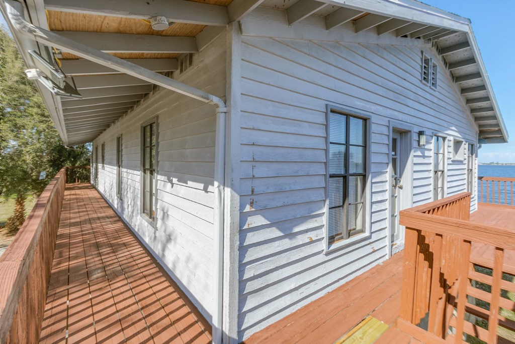 the side of a house with a wooden deck overlooking the ocean