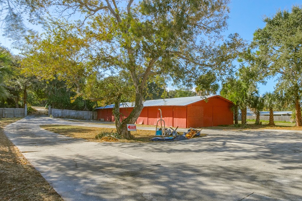 a red barn with a tree and a road in front of it