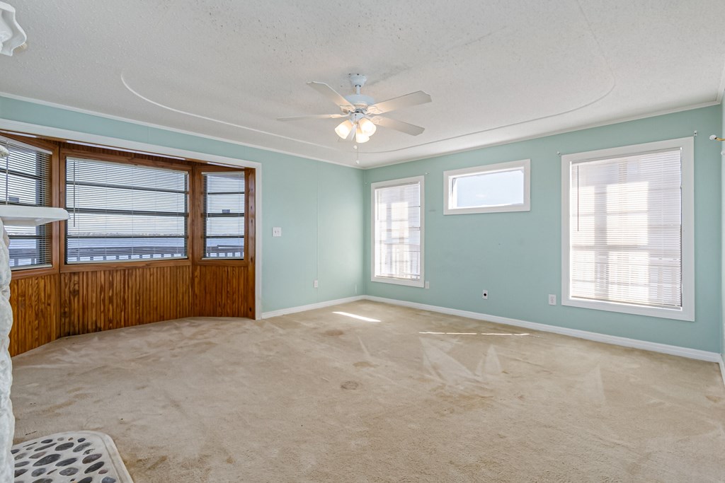 an empty living room with a ceiling fan and a window
